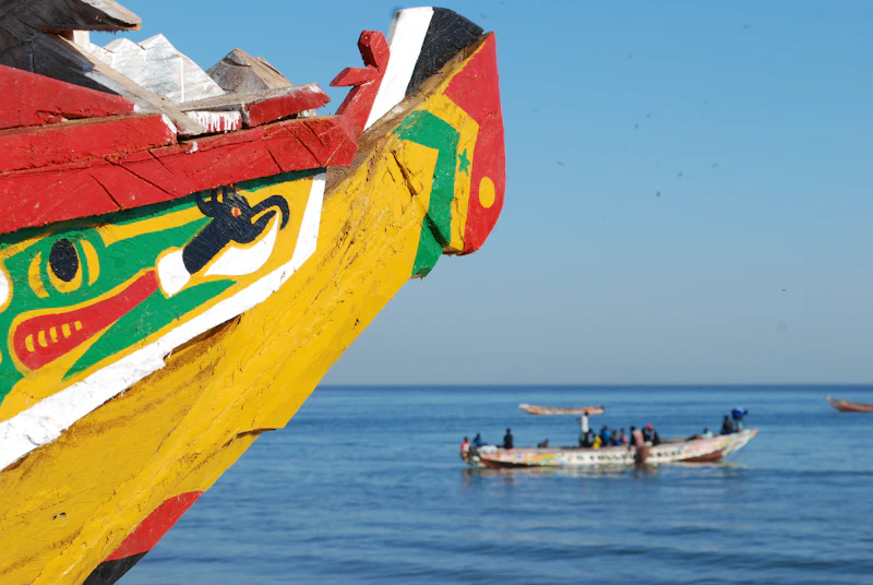 A painted fishing boat with a crew working at sea behind it